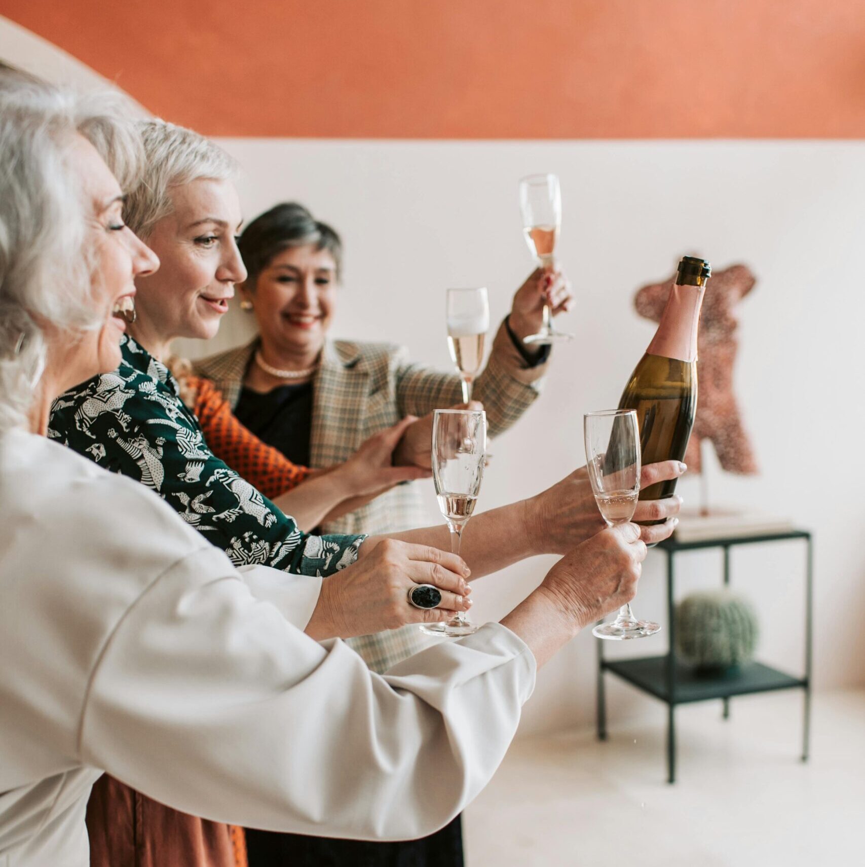 A joyful group of senior women toasting with champagne glasses indoors.